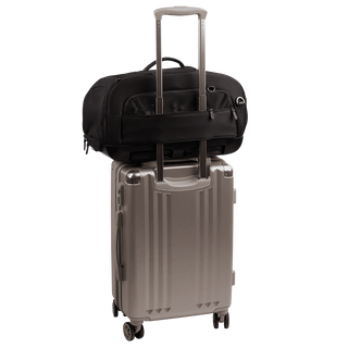 back view of compact, black pet car seat sitting on a silver, hardshell suitcase, secured with the carrier's trolley sleeve - view 7