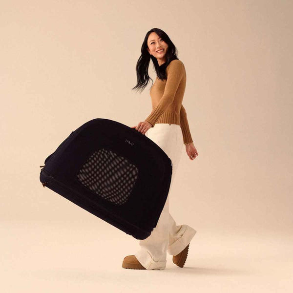 Stylish woman smiling while carrying the small Crispin pet car seat in her left hand