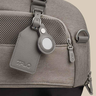 A close up of a Merle fashion Dupree shows the exterior pocket, the tracking device holder, and the luggage tag