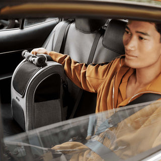 Man in taxi next to Kamella pet backpack with roll-up window in use.
