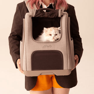 Pesron holds Kamella pet backpack in front of them while cat peers out from the rolled up window.