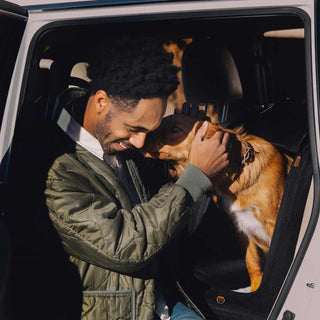 Man hugging a dog inside a vehicle